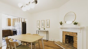 A modern kitchen with wooden cabinets, a dining table with chairs, a fireplace, and framed artwork on the wall. - Craftsman-style Starland District Gem ☆ Home Office & Back Yard ☆ Pet-Friendly (Savannah)