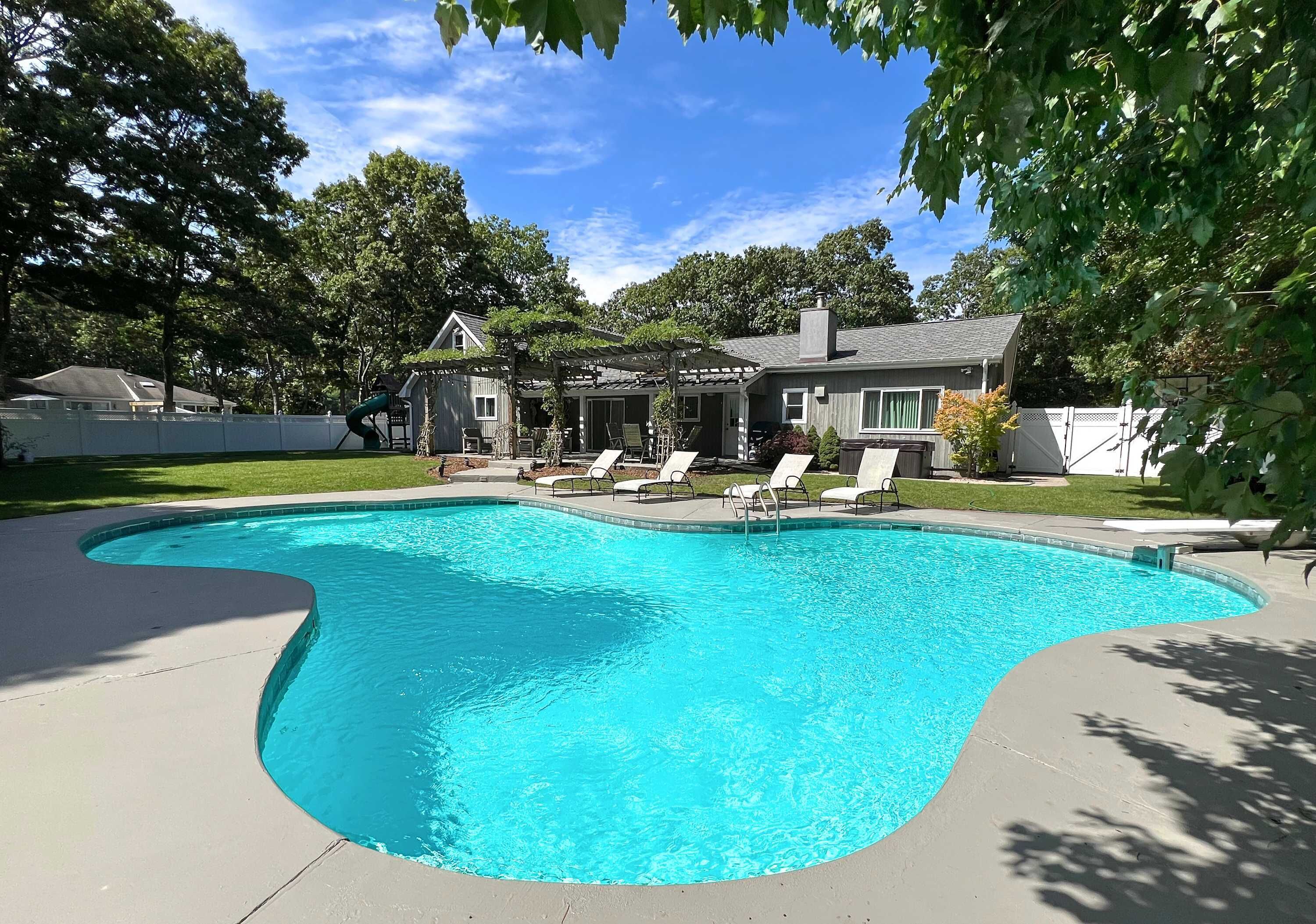 Une piscine résidentielle avec une maison en arrière-plan.