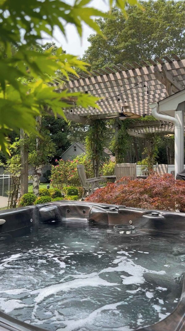A hot tub with a checkered roof structure and surrounding greenery.