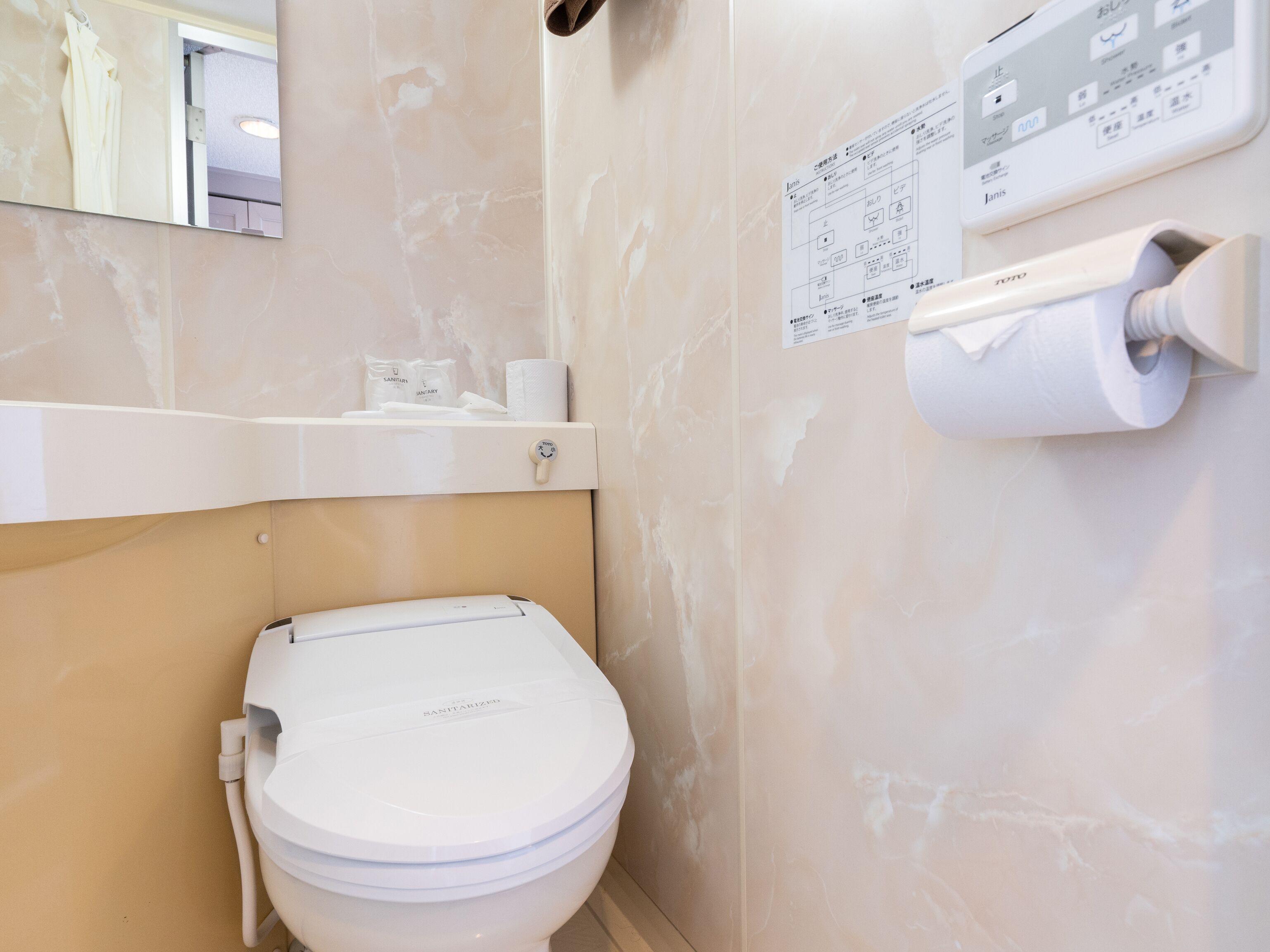A bathroom with a toilet, a hand dryer, and a paper towel dispenser.