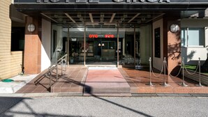 La entrada del Hotel Ginga, con un letrero visible, una puerta de cristal y un camino de baldosas que conduce a la entrada.