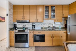 Eine Küche mit Holzausstattung, einem Edelstahlkühlschrank, einem eingebauten Backofen und einem Geschirrspüler.