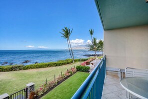 A balcony with a view of the ocean, a grassy area with flowers, and a clear sky. - Punahoa Beach 201 - Direct Ocean Front, Beautiful Renovation, Split AC, Wi-Fi (Kihei)