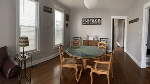 Un comedor con una mesa redonda de vidrio rodeada de sillas de madera, una lámpara y un letrero que dice 'Dream Big'.