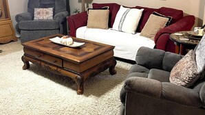 A living room with a red sofa, a blue armchair, a wooden coffee table, a lamp, and a framed deer painting. - Enjoy a cozy holiday getaway in our peaceful rural home.
WIFI NOT AVAILABLE (Mead)