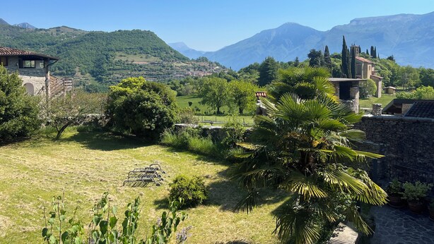 A rural landscape with a stone building, a church, and mountains in the background. - Holidayapartments in beautiful house, private garden, free Wi-Fi (Tignale)
