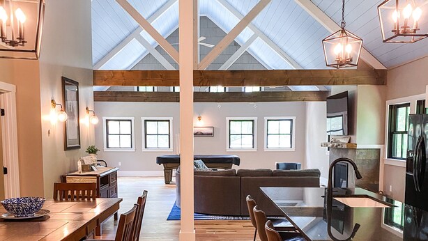 A spacious kitchen with a large island, wooden flooring, and a high ceiling with skylights.