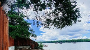 A beach with a wooden fence, rocks, and a calm water body.