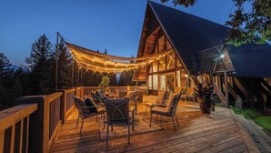 Eine Holzterrasse mit Sitzgelegenheiten und Lichterketten.