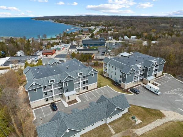 A multi-story residential building with a parking lot and a view of the sea. - Spacious Modern Condo in Door County w/ Spectacular Bay Views (Sister Bay)
