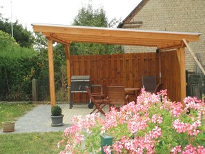 A covered patio area with a grill, seating, and potted plants. - Apartments Hehner first floor (Patersberg)