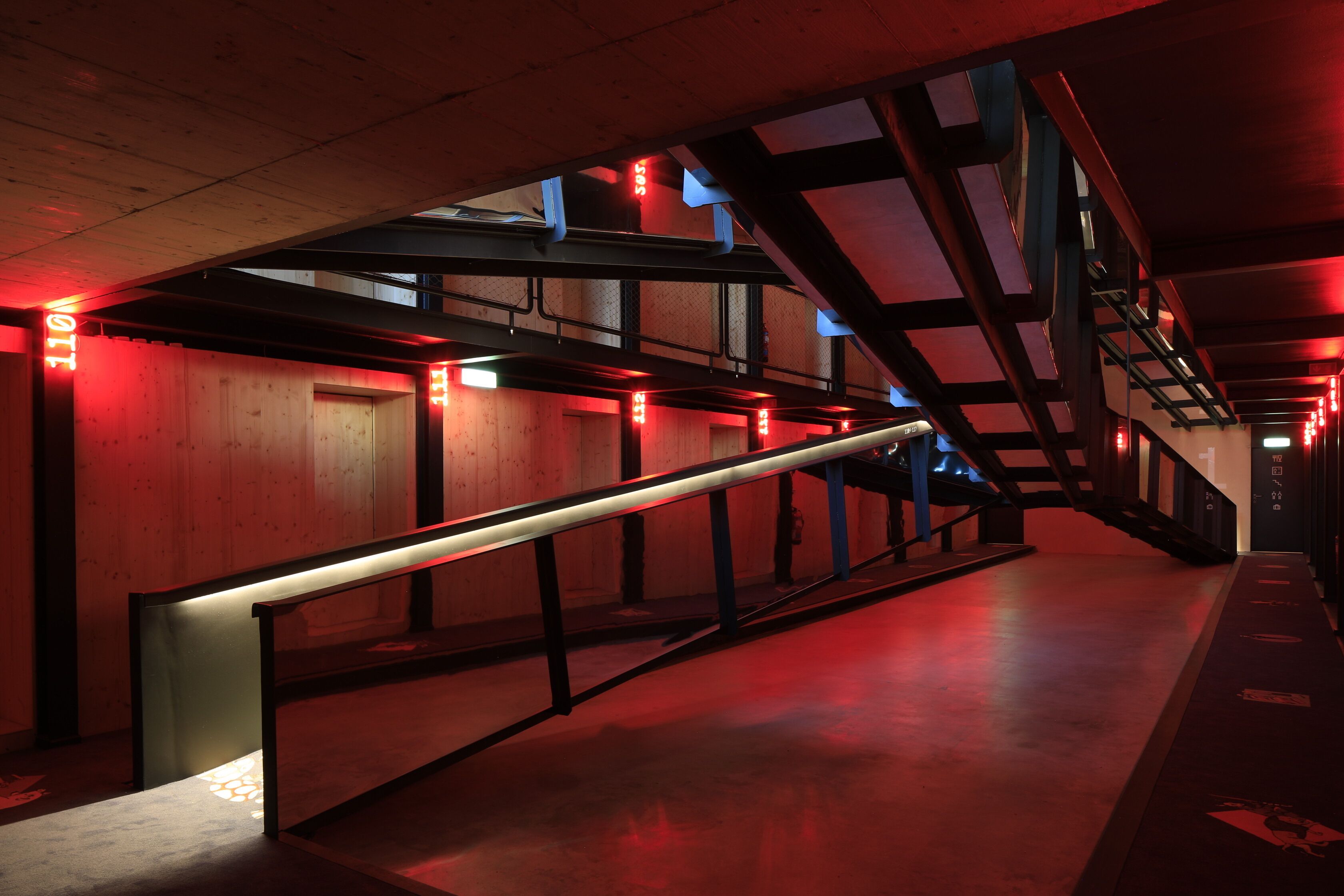 Um interior moderno com escada, painéis de madeira e iluminação vermelha.