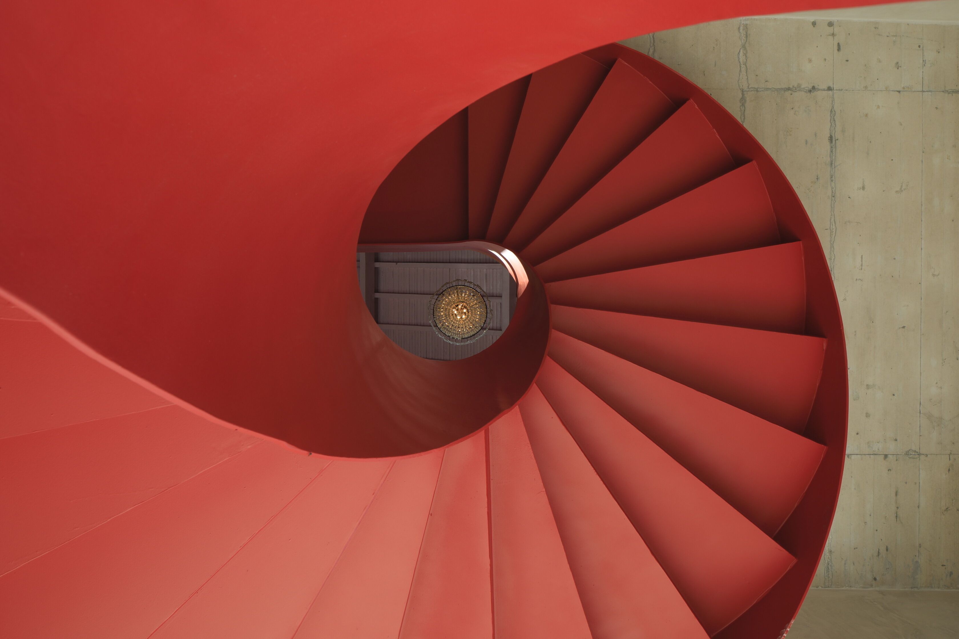 A spiral staircase with red steps and a central circular element.