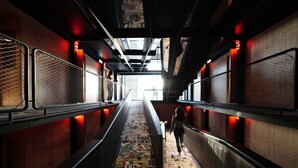 A corridor with a patterned floor, metal railings, and a person walking. - Zero Box Lodge Coimbra (Coimbra)