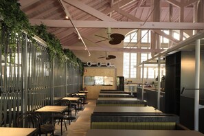 A restaurant with high ceilings, exposed beams, and a central bar area. - Zero Box Lodge Coimbra (Coimbra)