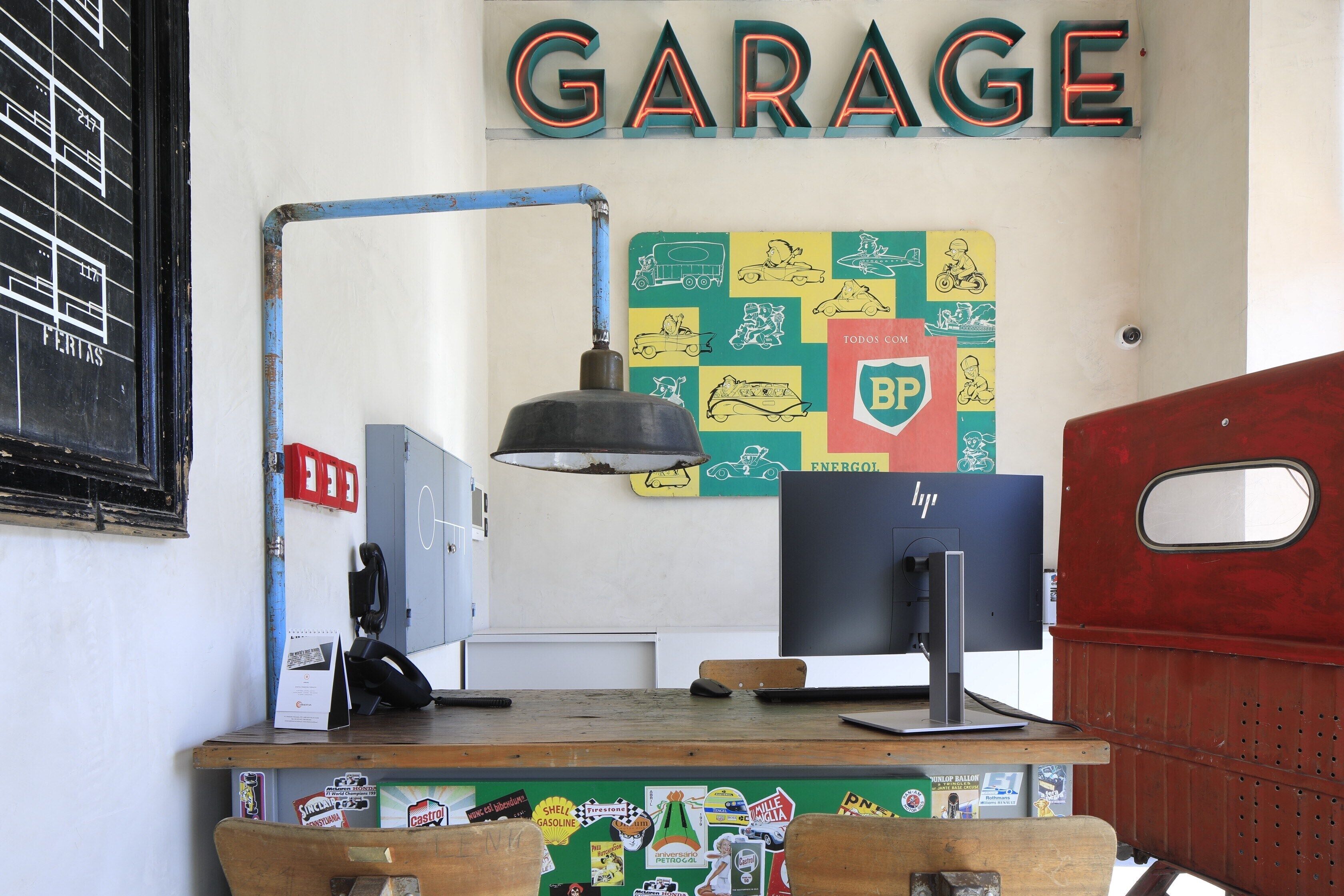 A garage with a computer, a lamp, and a wall with various stickers and a sign that says "GARAGE".