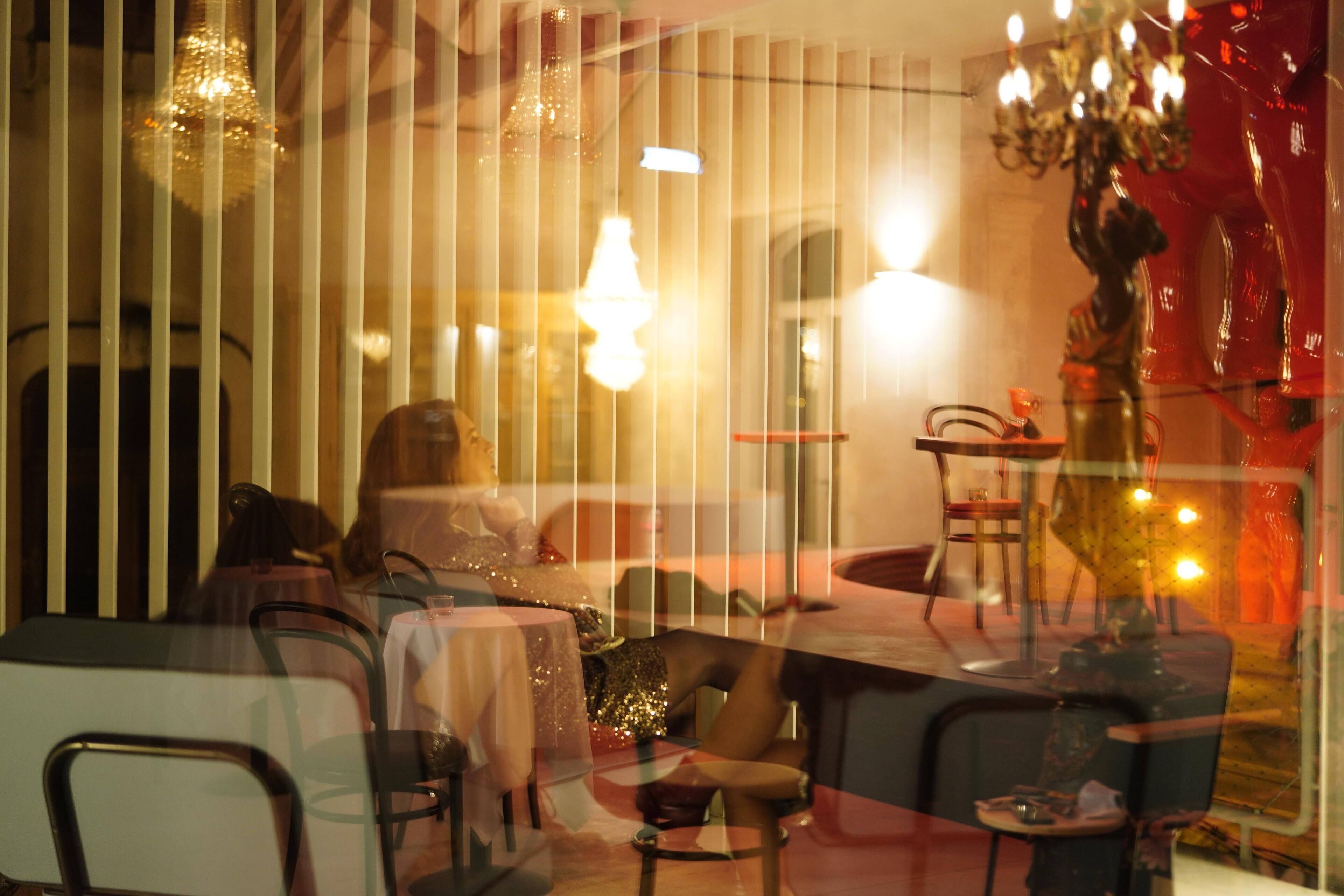 Interior de restaurante com mesas e cadeiras, uma estátua decorativa e um candelabro.