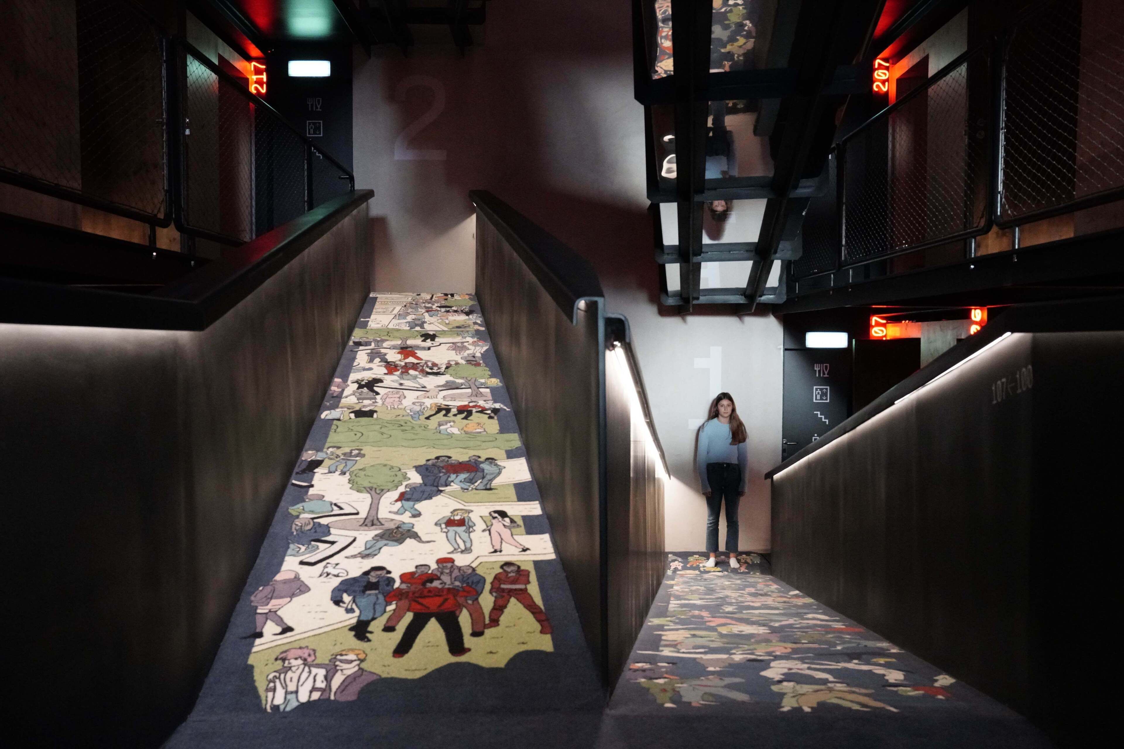 A staircase with a colorful comic strip design on the steps and a person standing at the top.