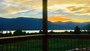 A balcony with a view of mountains and a lake during sunset. - MODERN RUSTIC CABIN WITH WATER ACCESS AND BOAT DOCK [SLEEPS 17] (West Yellowstone)