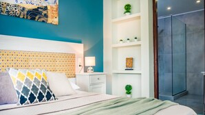 Une chambre à coucher moderne, avec un lit, une table de chevet, une lampe et une étagère murale agrémentée d’objets décoratifs.