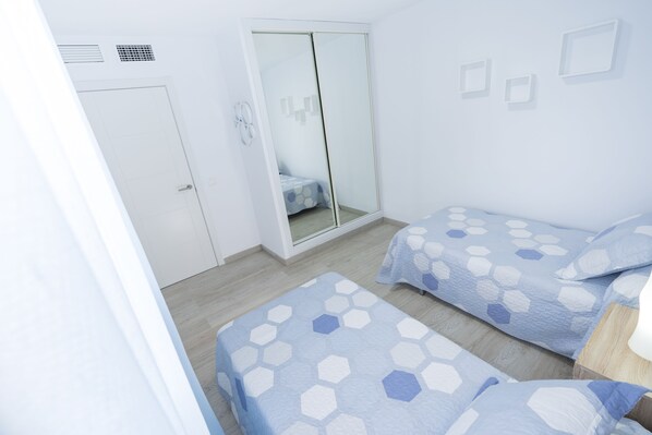Une chambre avec deux lits, une armoire et un miroir.