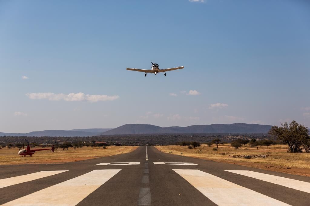 An airplane landing on a runway with mountains in the background.