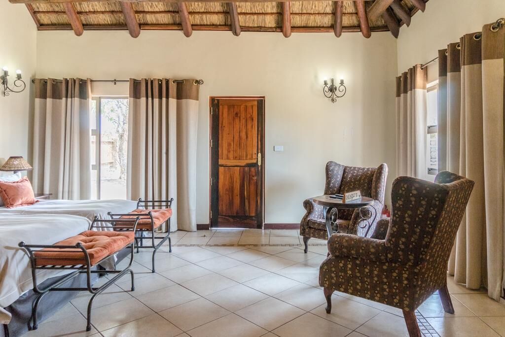 Une chambre d’hôtel avec deux lits, une petite table, une chaise et une porte en bois.