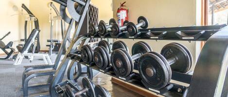 A gym with various weightlifting equipment, including dumbbells and a bench press.