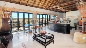 A spacious indoor area with a high ceiling, large windows, and a central bar area.