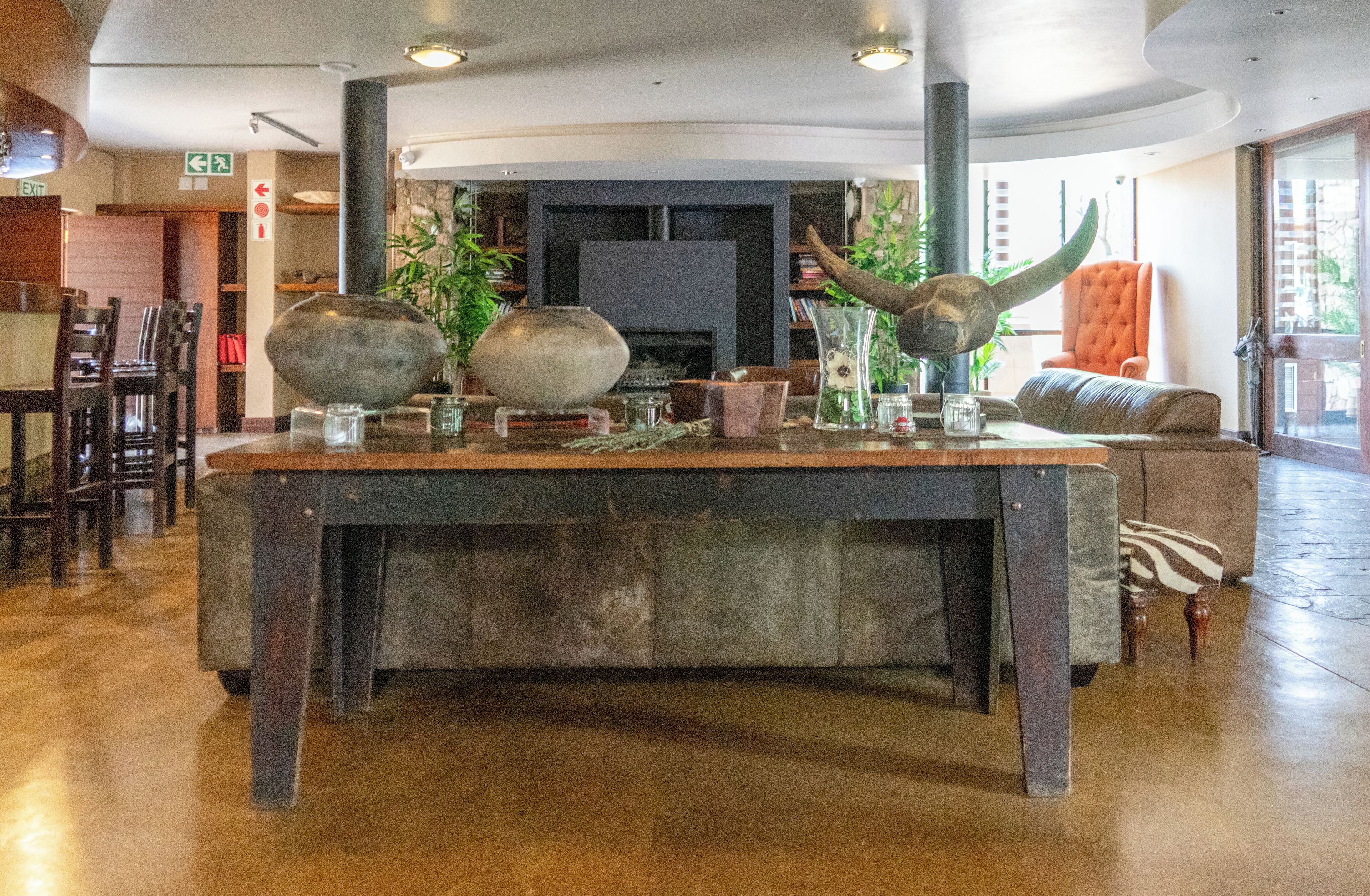 A reception area with a large wooden table, chairs, a sofa, and a television in the background.