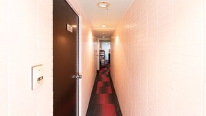 Un pasillo estrecho con paredes de azulejos blancos y una alfombra roja.