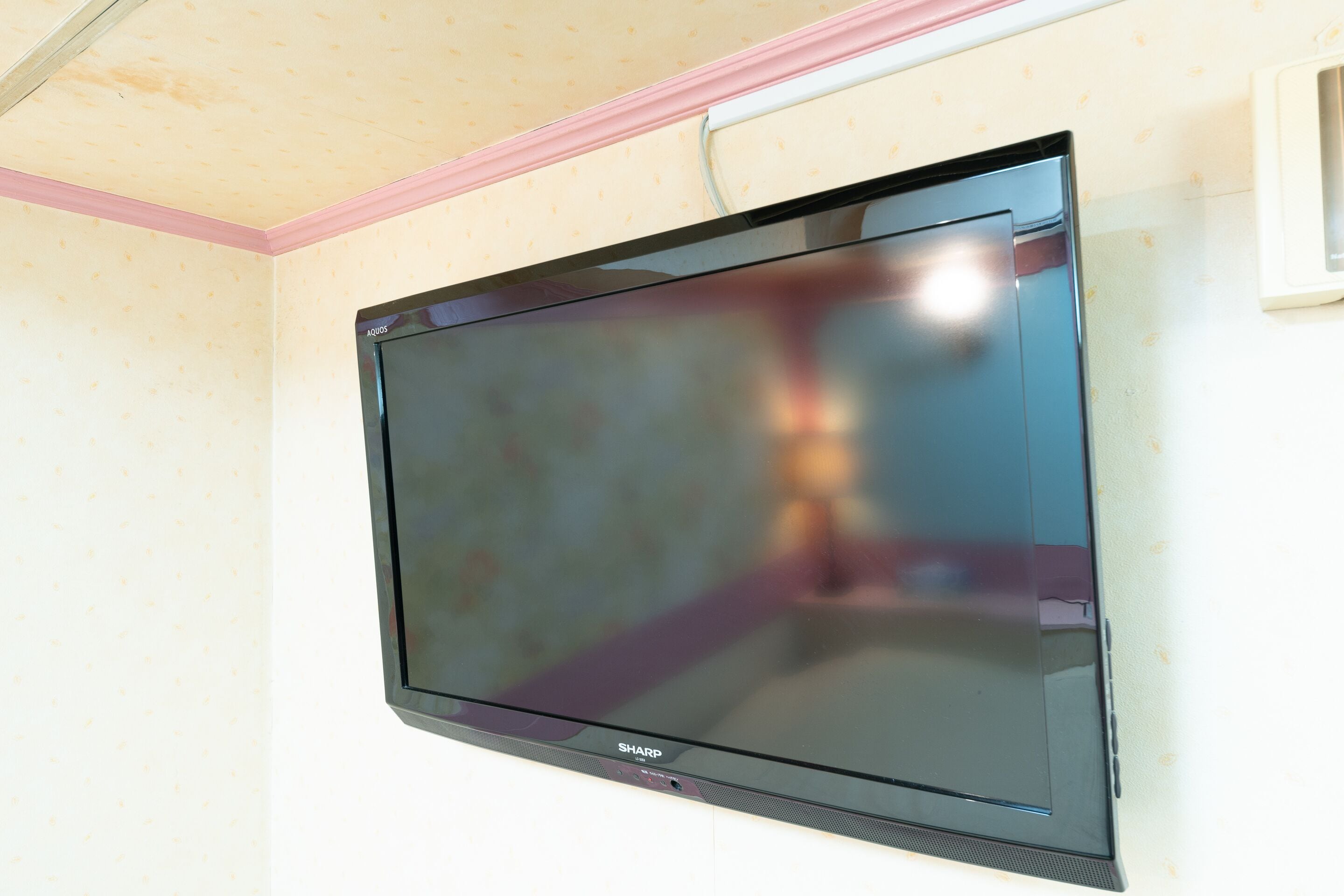 A flat-screen TV mounted on a wall with a pink trim.