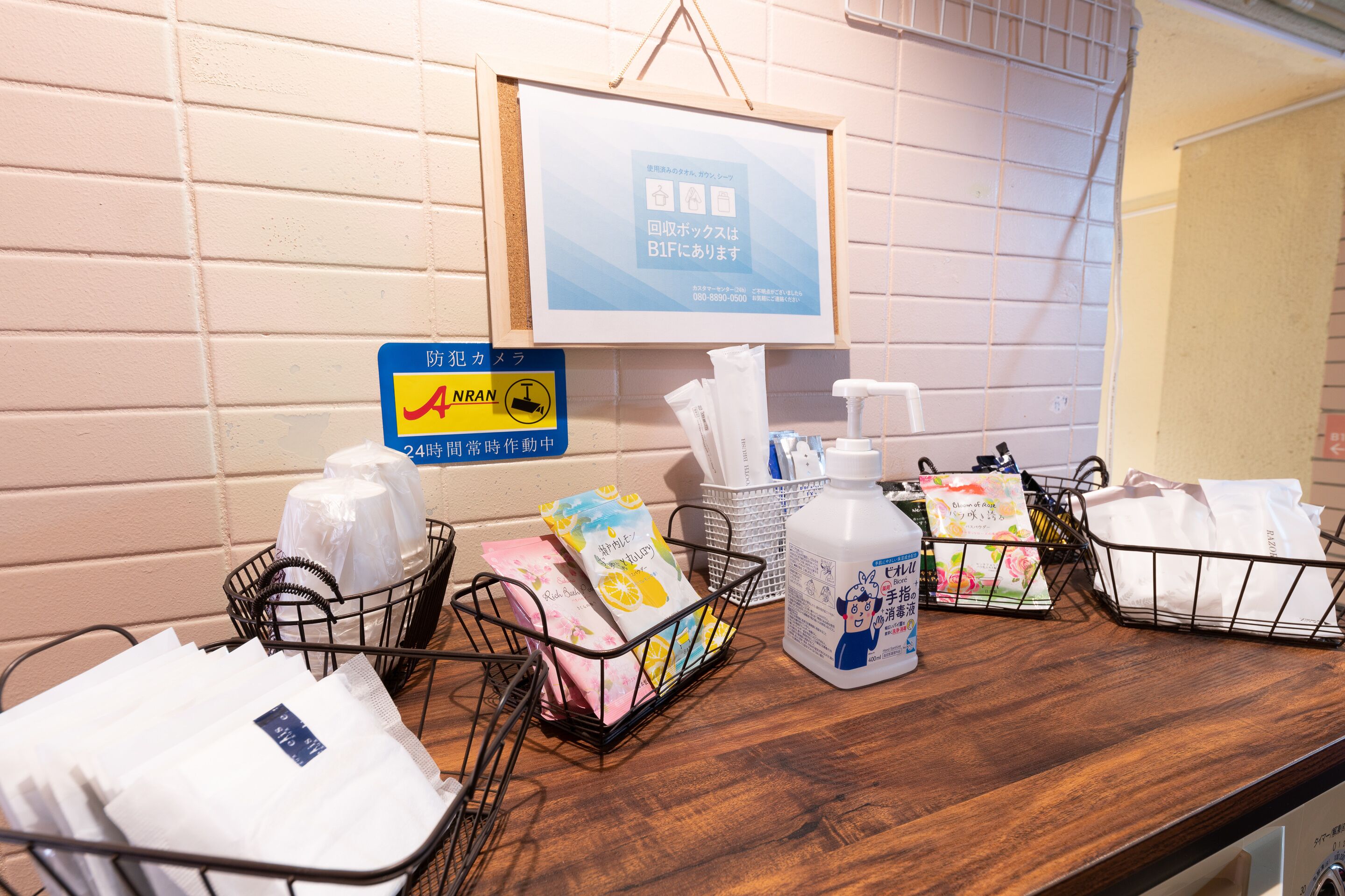 A hotel reception area with a wooden counter, baskets of toiletries, and a framed sign on the wall.