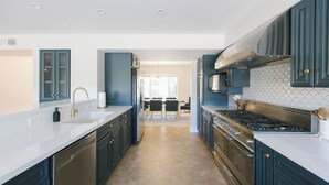 A modern kitchen with dark cabinetry, stainless steel appliances, and a white countertop.