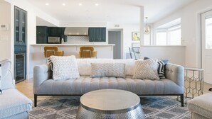 A modern living room with a grey sofa, round coffee table, and a kitchen in the background.