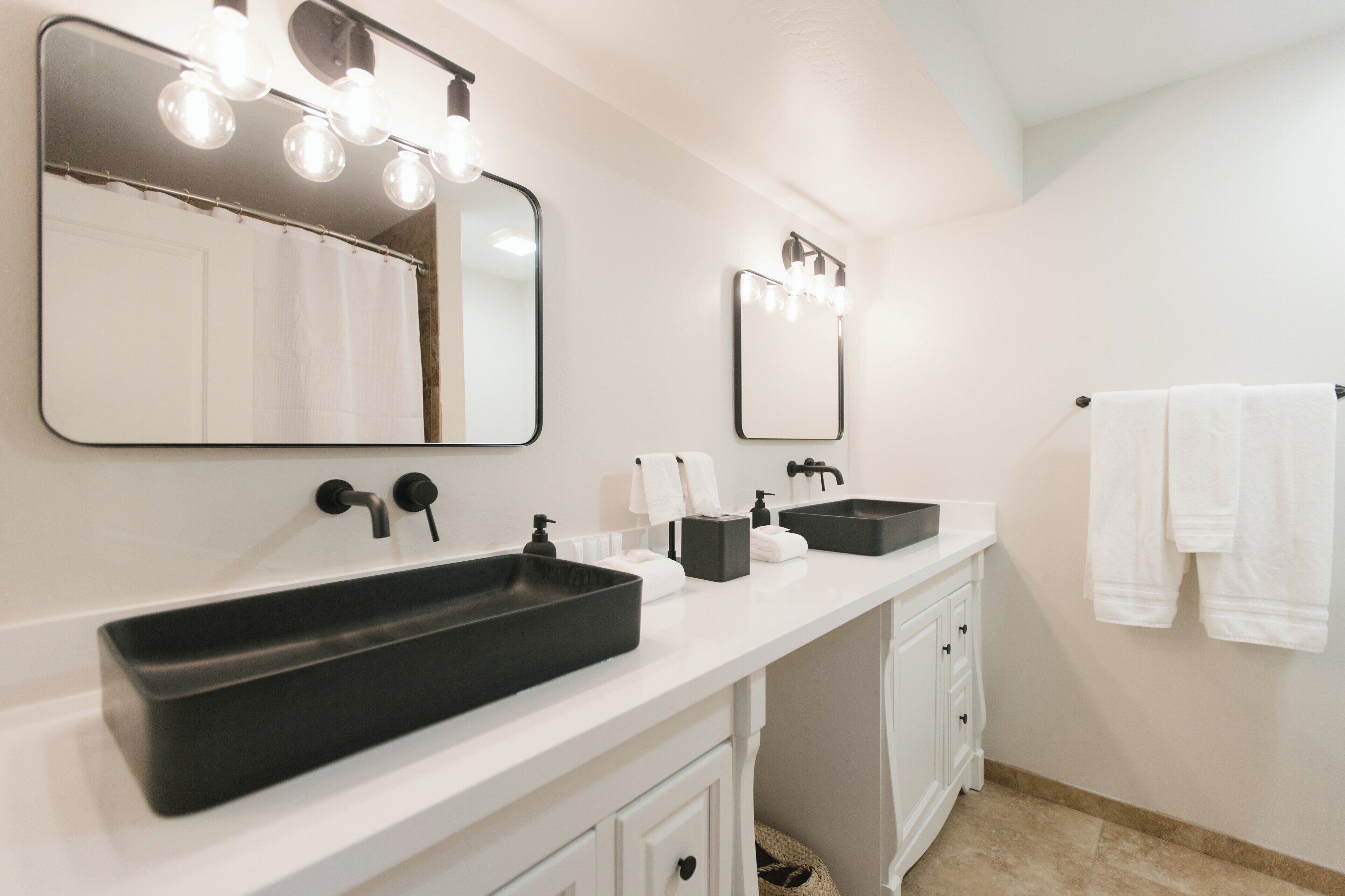 A bathroom with two sinks, a large mirror, and a towel rack.