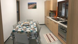 Cocina compacta con mesa, microondas y estufa.