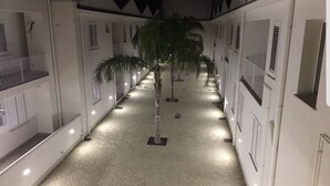 A corridor with a central palm tree, flanked by white buildings with windows and doors. - Vacation home "Fortuna " (Balestrate)