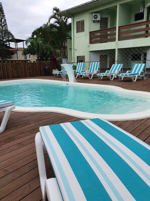 Una piscina con sillas de descanso y una terraza de madera.