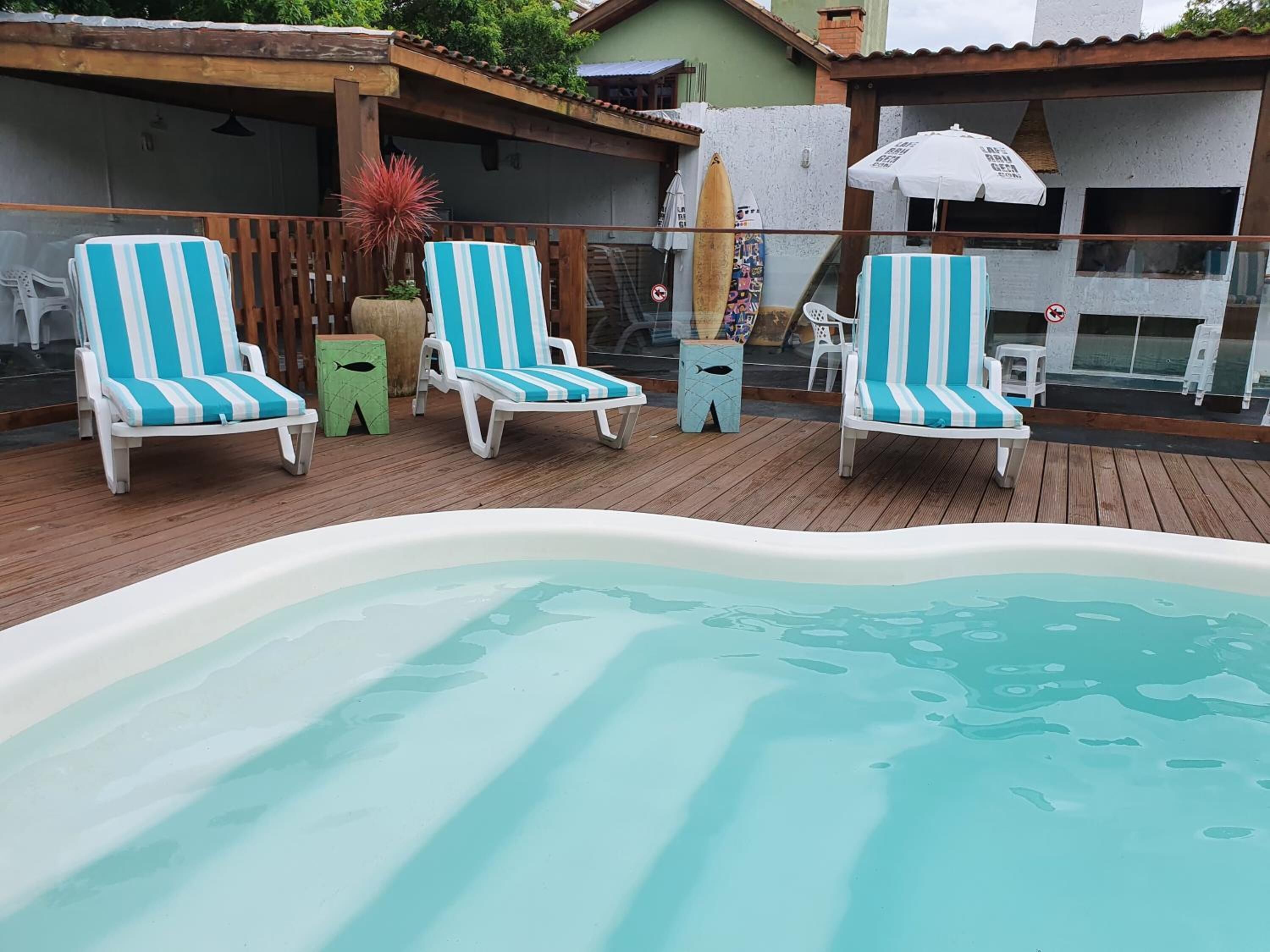 Uma área de piscina com quatro espreguiçadeiras listradas e uma pequena banheira de hidromassagem.