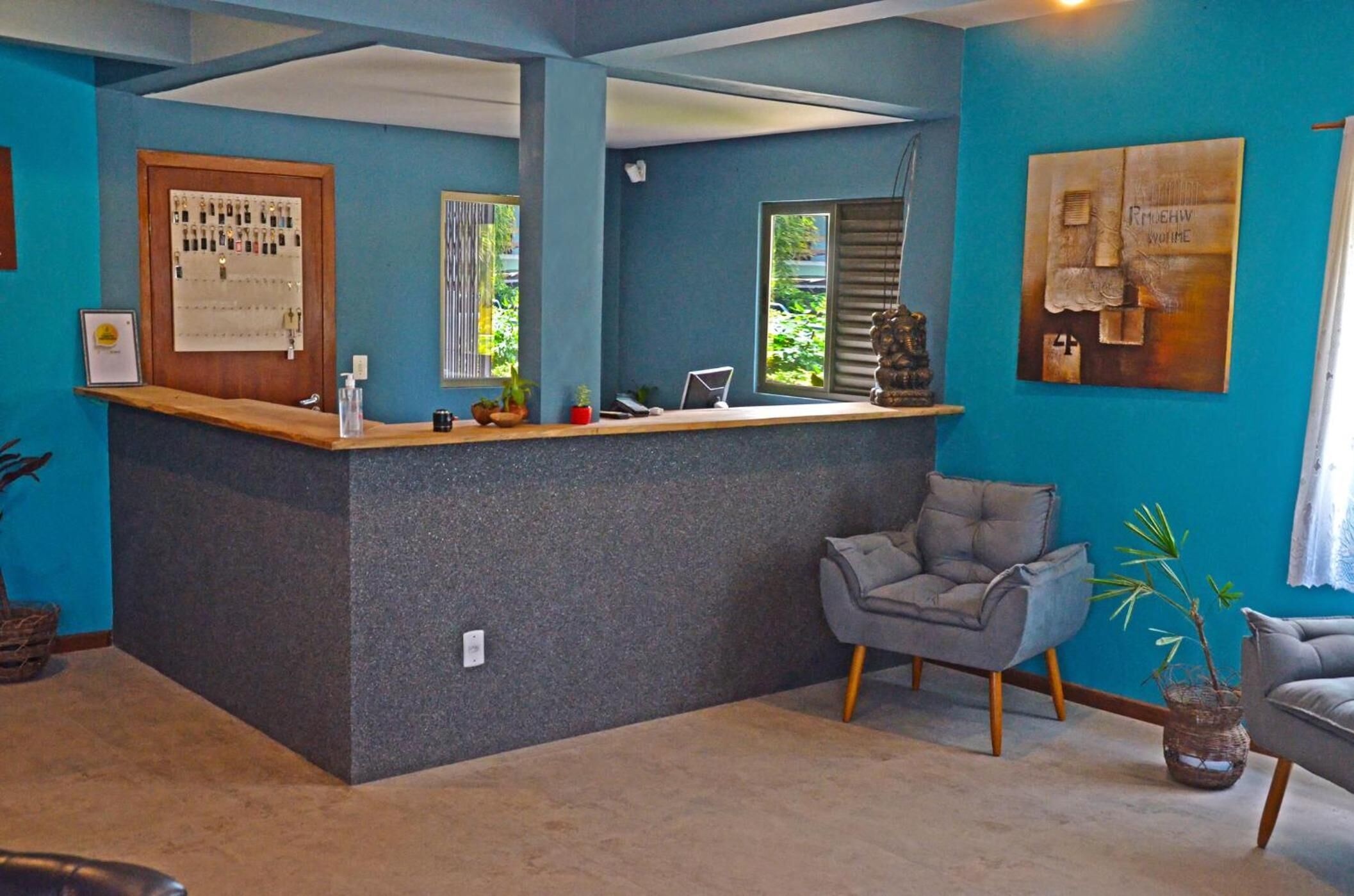 A reception area with a wooden desk, a grey armchair, and a potted plant.
