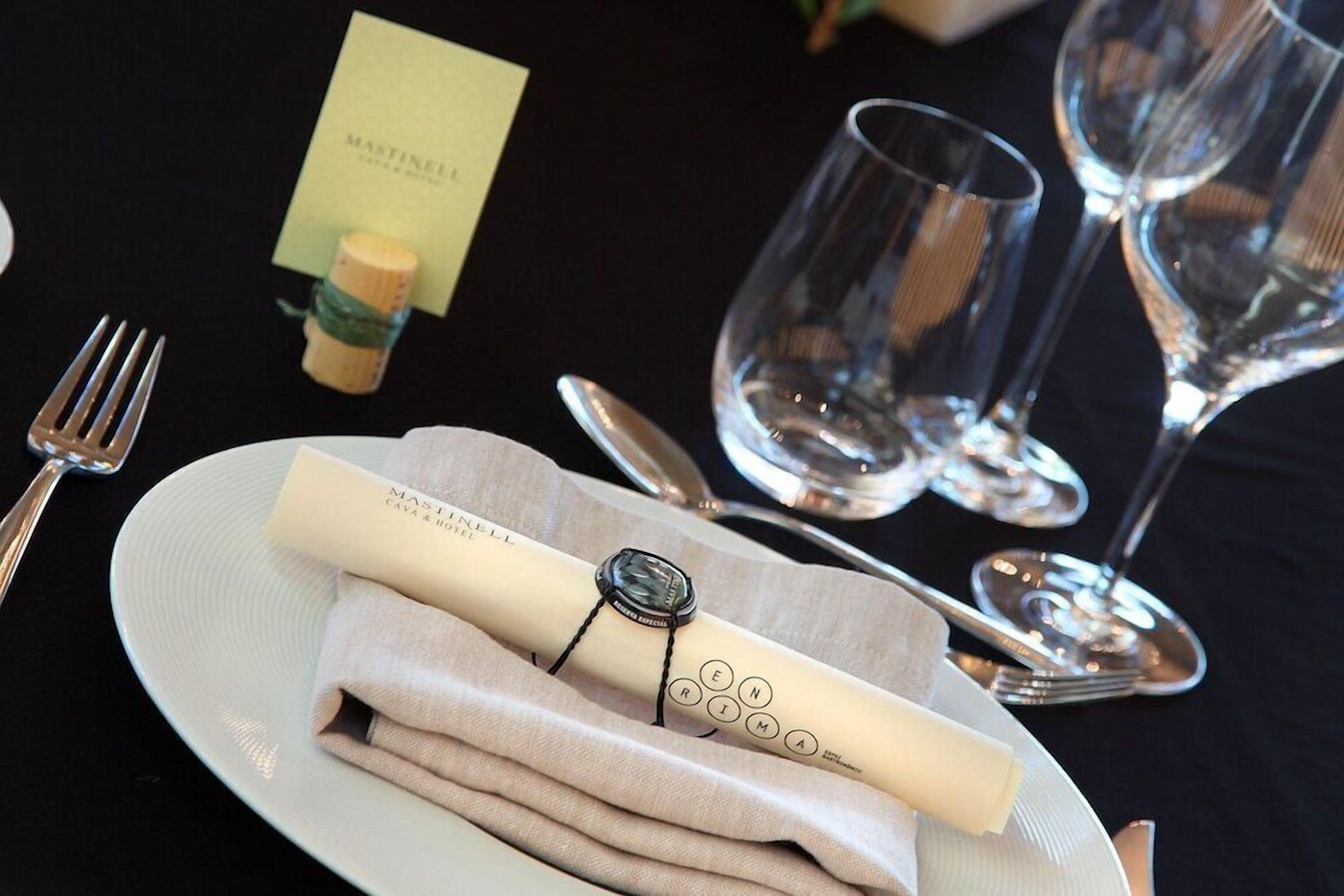 A table setting with a folded napkin, a corkscrew, wine glasses, and cutlery.