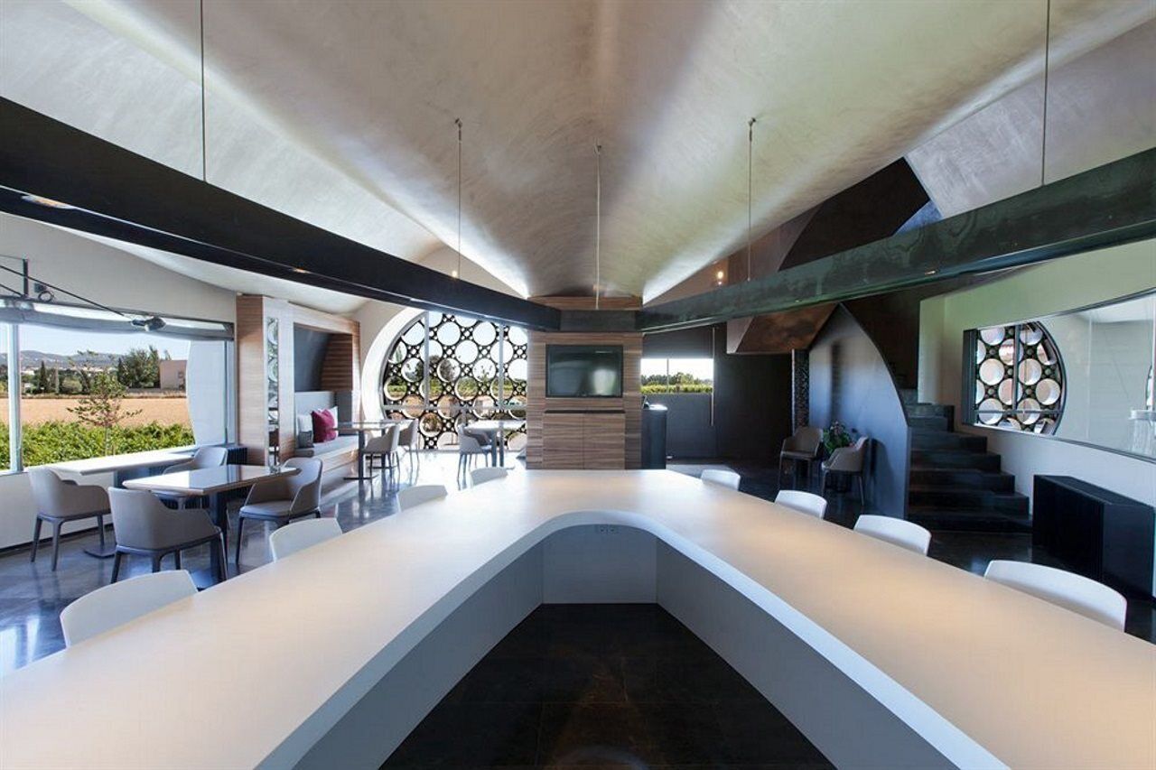 A modern kitchen with a curved island, large windows, and a view of the outdoors.