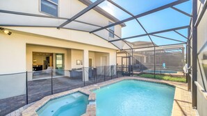 Una piscina con idromassaggio, delimitata da una recinzione in vetro e con una zona patio coperta.