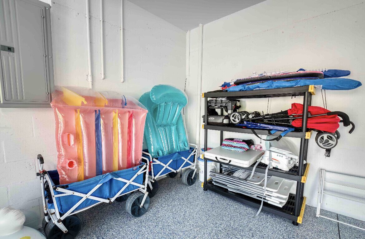 A room with a cart containing inflatable items, a shelf with gear, and a wall-mounted rack with skis.