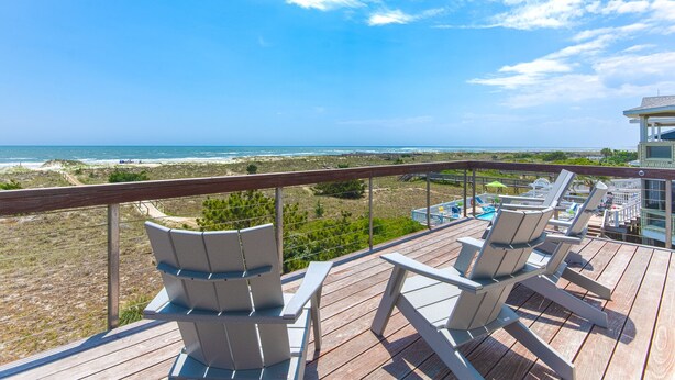 A wooden deck with white lounge chairs overlooking a beach and ocean. - "Aqualuxe" Luxury oceanfront 6 bedroom, 5.5 bathroom home with New Pool for 2022 Season (Holden Beach)