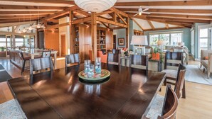 A spacious living area with a central island, wooden beams, and a large ceiling fan. - "Aqualuxe" Luxury oceanfront 6 bedroom, 5.5 bathroom home with New Pool for 2022 Season (Holden Beach)