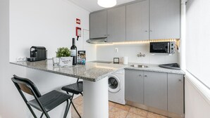 Cucina compatta con piano di lavoro in granito, lavatrice, forno a microonde e macchina per il caffè.
