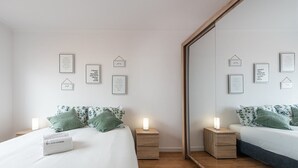 Una camera da letto moderna con due letti, comodini e un ampio specchio.