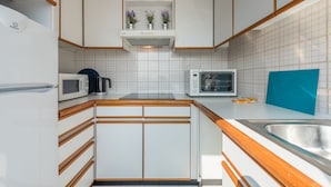 A compact kitchen with white cabinets, a microwave, a toaster, and a sink. - GuestReady - Porto Magic View (Vila Nova de Gaia)